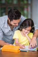 Happy father assisting daughter with homework