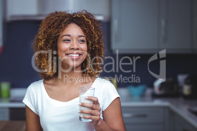 Smiling young woman holding glass of milk