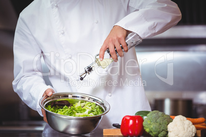 Chef putting oil on salad