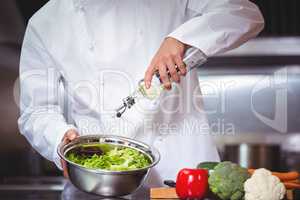 Chef putting oil on salad