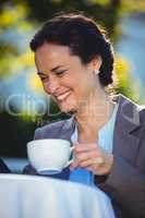 Pretty businesswoman using tablet and having a coffee