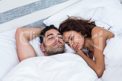 Couple with eyes closed while sleeping on bed