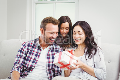 Parents and daughter looking at gift box