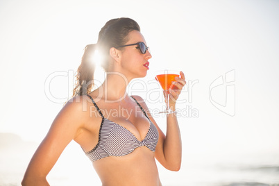Glamorous woman having a cocktail drink on the beach