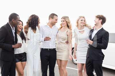 Well dressed people posing next to a limousine