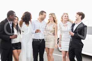 Well dressed people posing next to a limousine