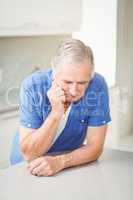 Depressed senior man leaning on table