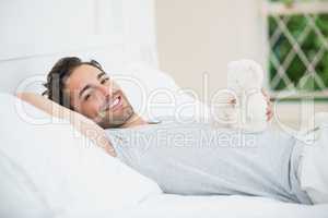 Man holding teddy bear while relaxing on bed