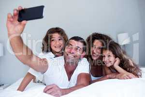 Happy family taking a selfie on bed