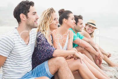 Group of friends sitting side by side on the beach