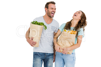 Happy young couple holding bag of vegetables