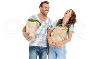 Happy young couple holding bag of vegetables