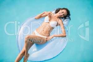 Beautiful young woman relaxing on swim ring