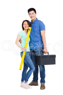 Young couple standing with spirit level measuring tool and tool