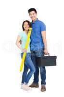 Young couple standing with spirit level measuring tool and tool