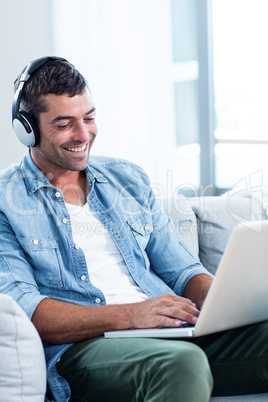 Young man listening to music while using laptop Young man listening to music while using laptop