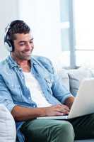 Young man listening to music while using laptop