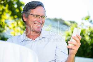Casual businessman looking at smartphone smiling