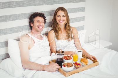 Portrait of young couple having breakfast on bed