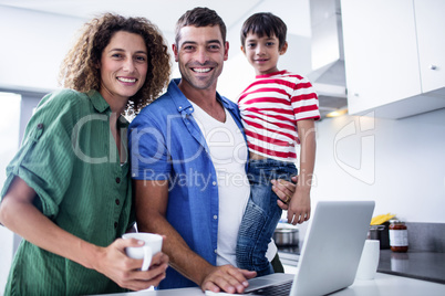 Parents using laptop with son in kitchen Parents using laptop with son in kitchen