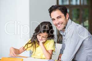 Portrait of smiling father assisting daughter with homework