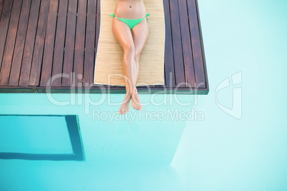 Beautiful woman in green bikini relaxing by poolside