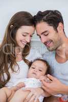 Close-up of happy couple with baby on bed