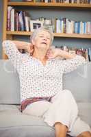 Senior woman suffering from neck pain on sofa