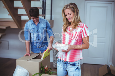 Smiling woman unpacking bowls from box with man