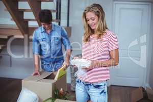 Smiling woman unpacking bowls from box with man