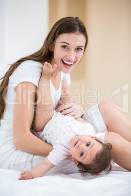 Portrait of smiling mother holding baby on bed