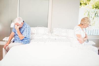 Depressed couple sitting on bed at home