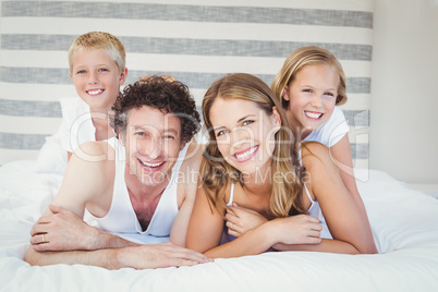 Portrait of happy family resting on bed