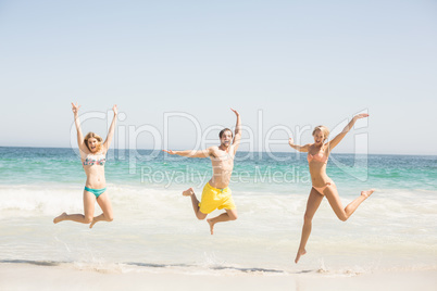 Happy young friends jumping on the beach