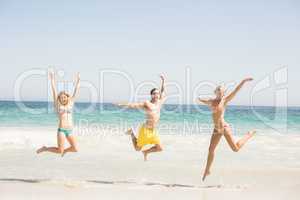 Happy young friends jumping on the beach