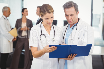 Two doctors looking at clipboard and discussing