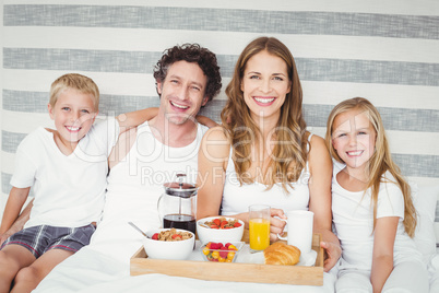 Portrait of happy family having breakfast on bed