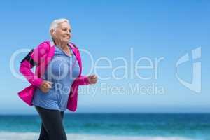 Focused mature woman running and listening to music