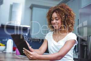 Young woman using digital tablet in kitchen