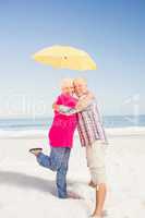 Senior couple embracing and holding umbrella