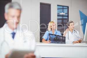 Female doctors with X-ray while working at computer desk