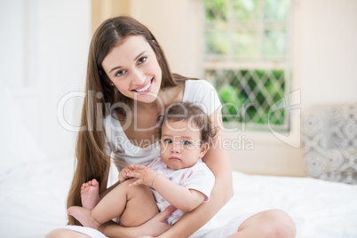 Smiling mother carrying daughter at home