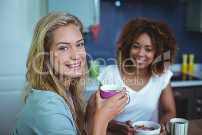 Woman drinking coffee with female friend at table