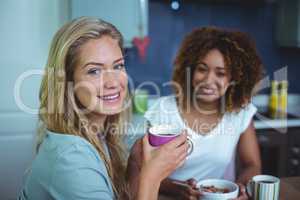 Woman drinking coffee with female friend at table