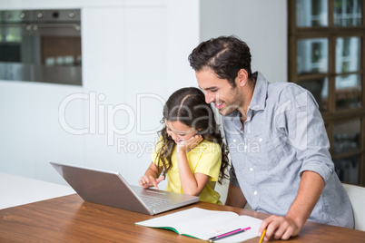 Smiling daughter working on laptop with father