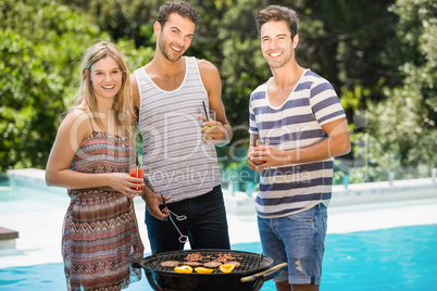 Happy friends preparing barbecue near pool