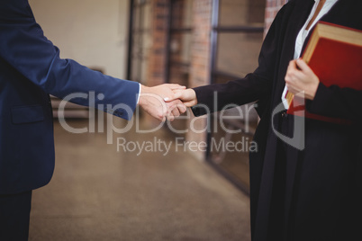 Midsection of female lawyer handshaking with client