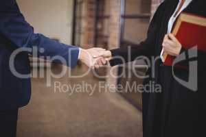 Midsection of female lawyer handshaking with client