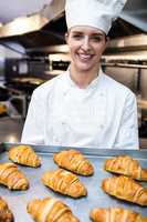 Portrait of a chef holding tray of croissants