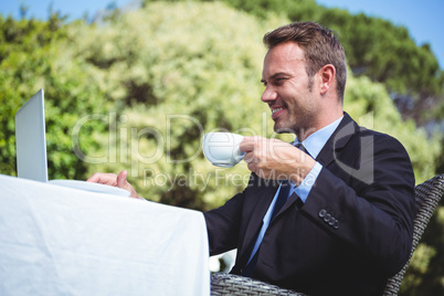 Businessman using laptop and having a coffee